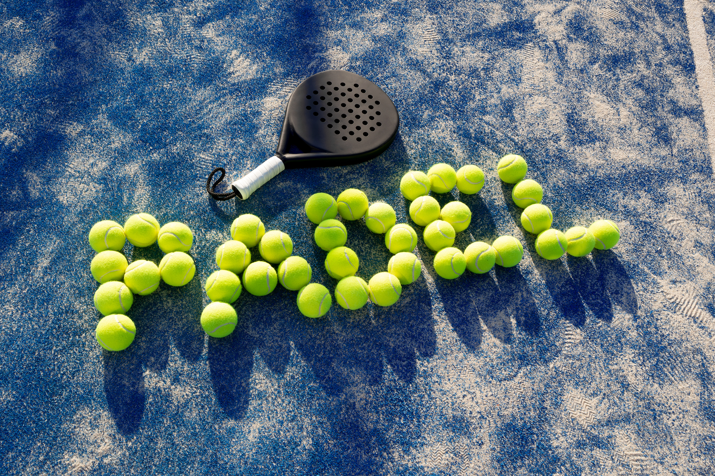 paddle tennis racket and balls on the blue paddle court